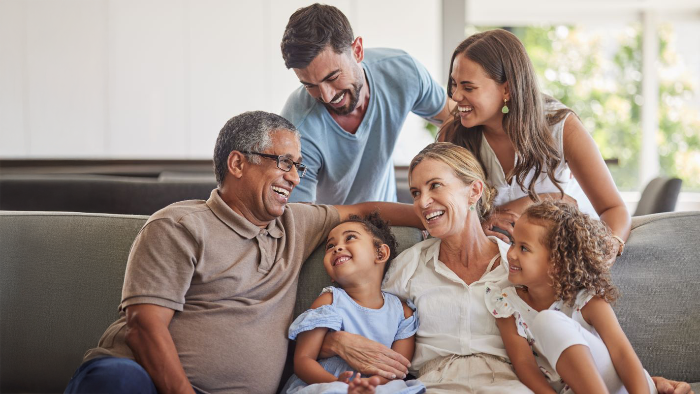 Intergenerational family seating at a couch smiling