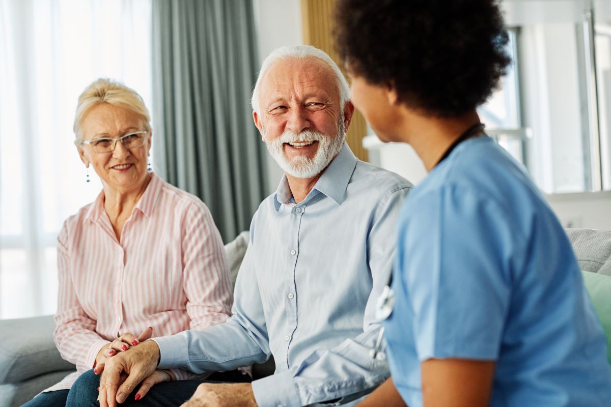 Elderly couple talking to a nurse smiling